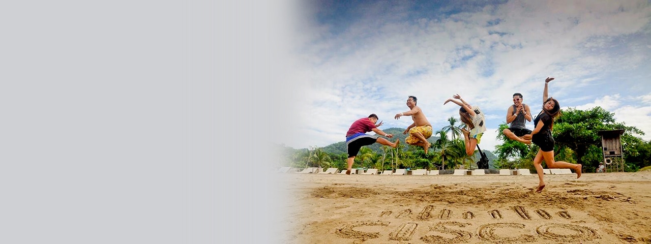 Five people jumping in the air above a Cisco Logo sign written in sand.