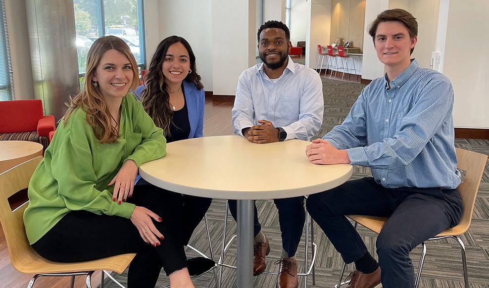 Four people sit together in an office setting.