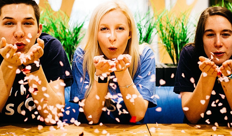 Male and two females blowing confetti from their palms in celebration from Cisco office in Raleigh, North Carolina