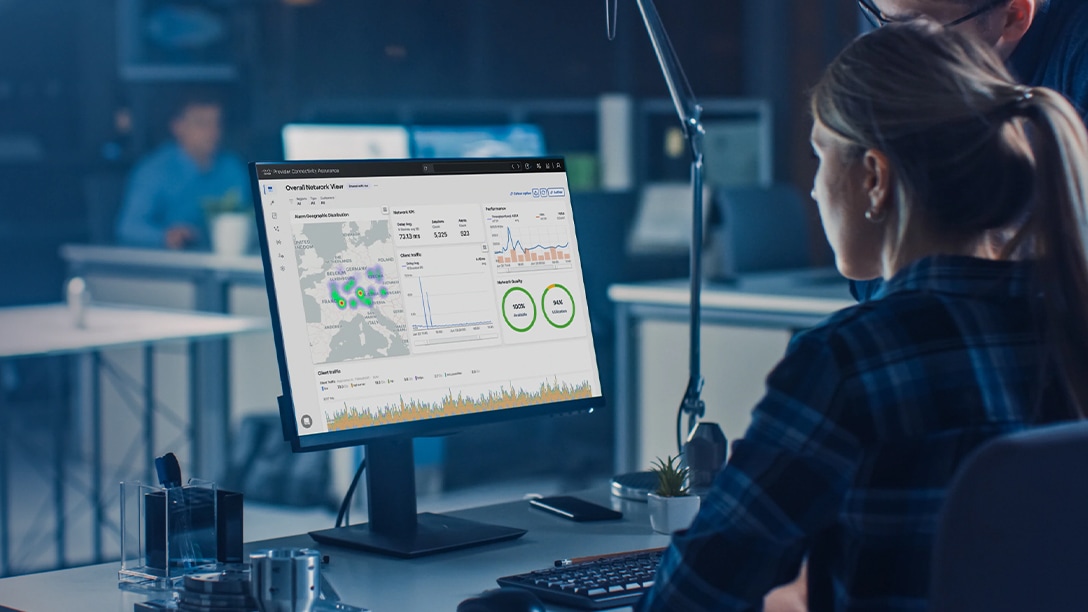 Two workers at a desk reviewing a Provider Connectivity Assurance dashboard