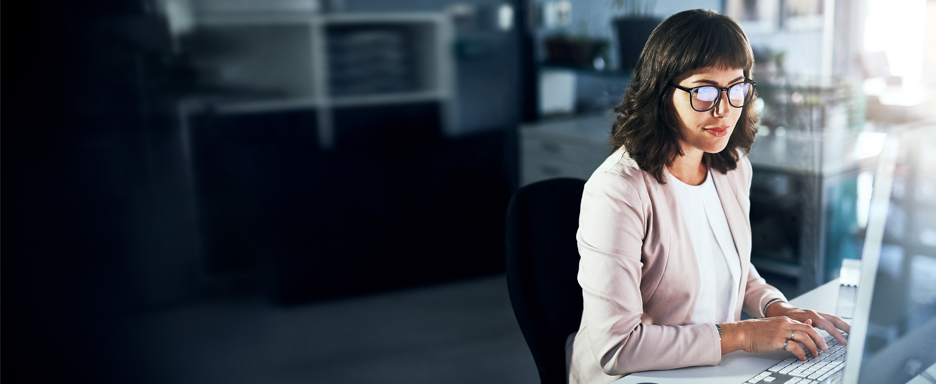 Person in an office setting, typing while viewing a desktop monitor