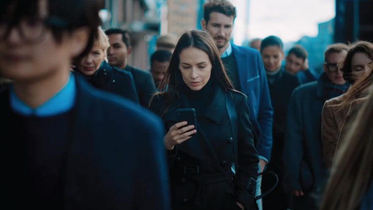 Femme regardant son téléphone portable sur un trottoir bondé